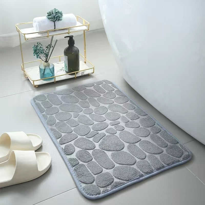Grey textured bath mat on a bathroom floor