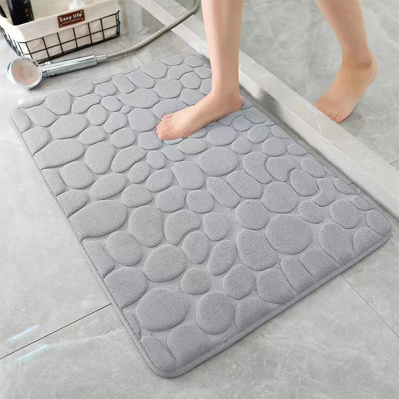 Gray textured bath mat on a bathroom floor with a person stepping onto it.